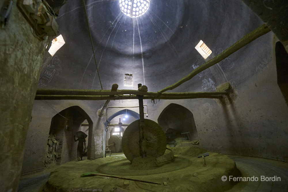 Nella città di Yazd costruita in adobe (mattoni di fango e paglia), definita "la sposa del deserto", da oltre 700 anni continua un'antica e quasi immutata attività... 
quella dei Mazari , "i mugnai" dell'hennè. 
Gli antichi mulini a pietra, un tempo trainati da asini, sono tuttora utilizzati per la macinatura delle foglie di hennè. 
La secolare tecnica di lavorazione, è particolarmente apprezzata dai paesi arabi ai quali è destinata la maggior parte  di questa polvere verde 
utilizzata per la tintura dei capelli  delle donne. 